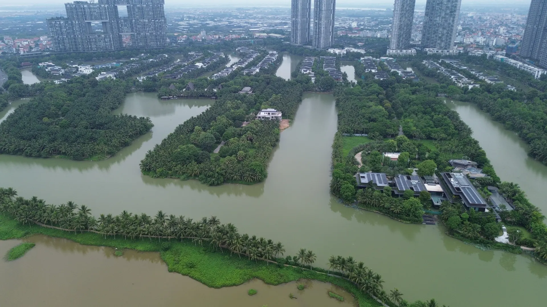 Flycam các đảo biệt thự Ecopark Grand The Island giữa kênh nước, hàng dừa và các toà tháp phía xa