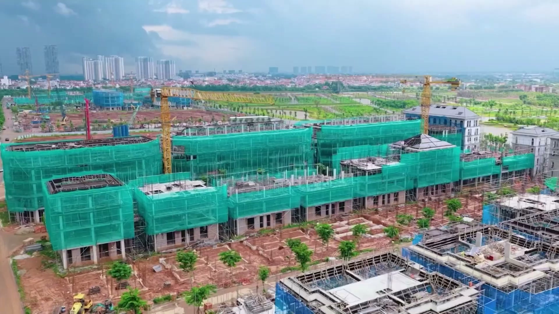 Công trường Alluvia City nhìn từ trên cao, dãy shophouse phủ lưới xanh đang xây và cẩu tháp