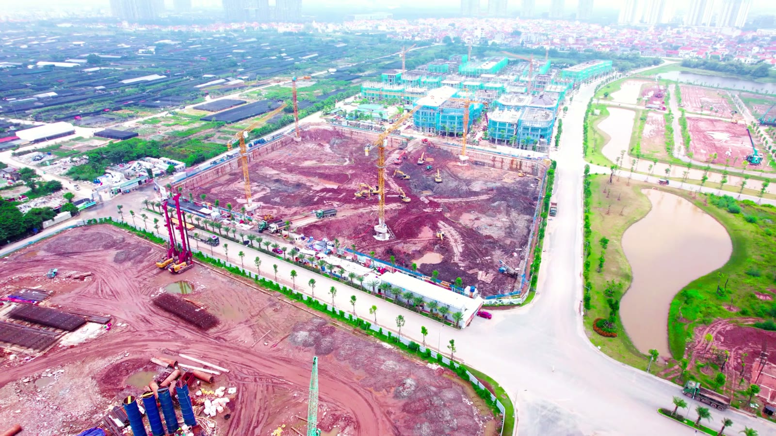 Đại công trường khu cao tầng Alumi Premium Alluvia City nhìn từ trên cao, hố móng đỏ và nhiều cẩu tháp đang thi công phần hầm