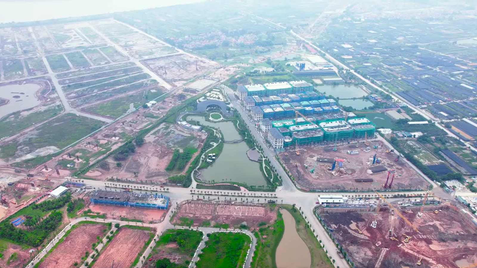 Công trường Alluvia City bên bờ sông Hồng nhìn từ trên cao, các dãy biệt thự phủ lưới xanh nằm cạnh hồ cảnh quan đã tạo hình