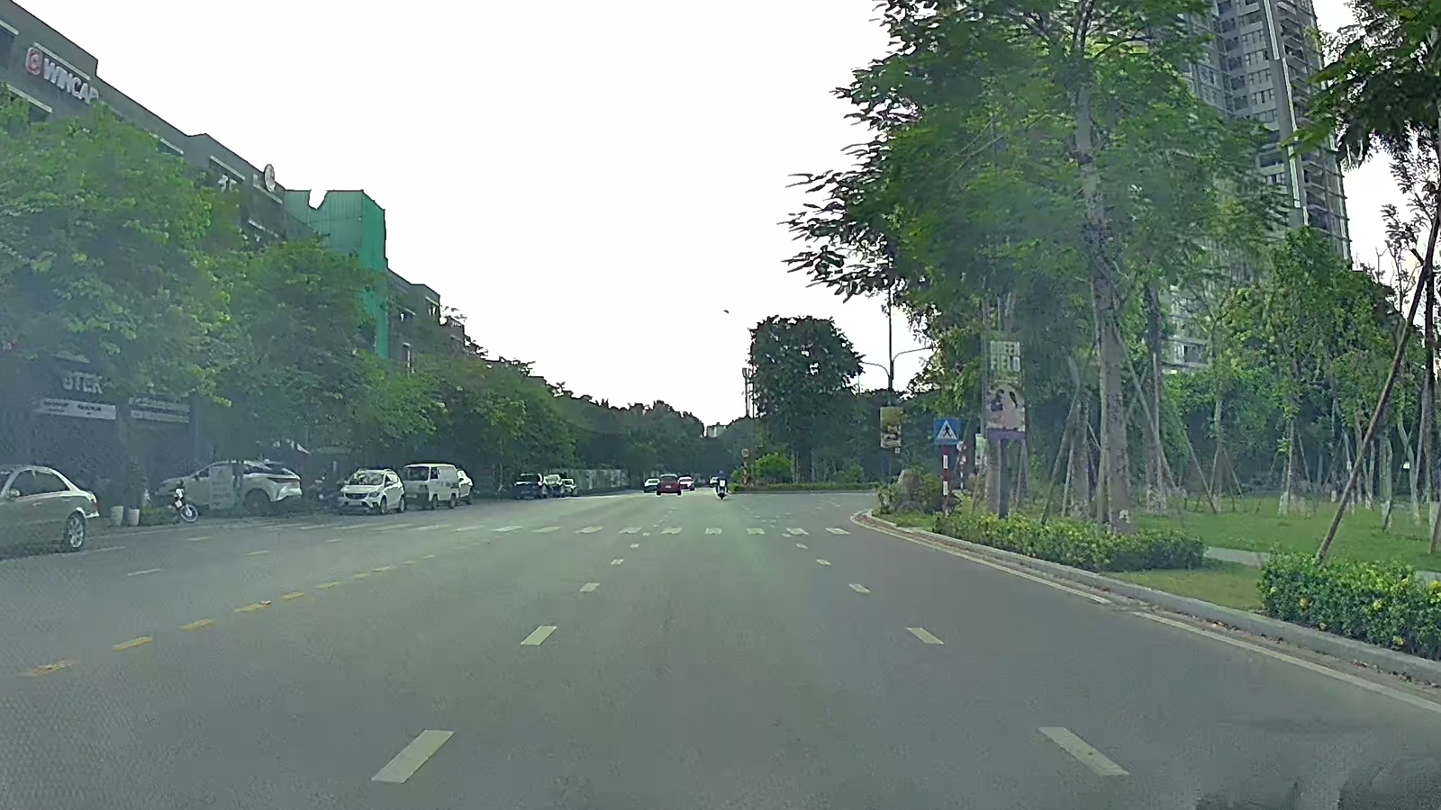 Đường nội khu nhiều làn trong khu đô thị Ecopark, một bên là dãy nhà thấp tầng có mặt tiền kinh doanh, một bên là hàng cây và tòa căn hộ cao tầng