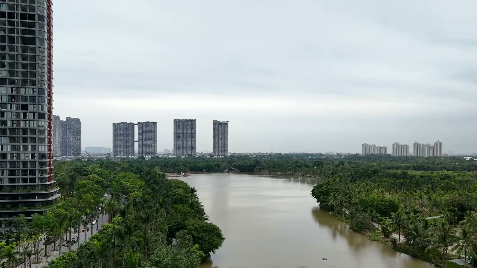 Hồ nước và mảng cây xanh giữa khu đô thị Ecopark Văn Giang, một tòa căn hộ cao tầng đứng sát mép hồ