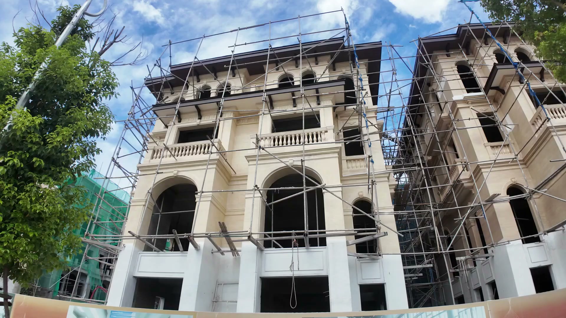 Hai căn biệt thự song lập thương mại Alluvia City đang quây giàn giáo, chụp từ dưới lên thấy rõ mặt đứng liền khối và các ô cửa vòm