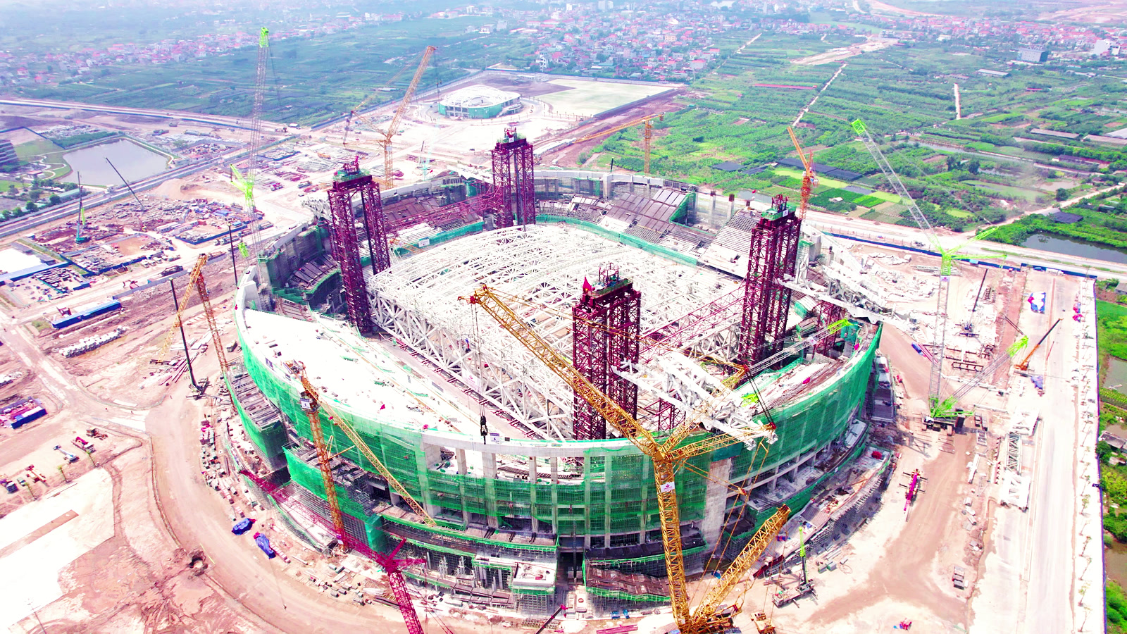 Bốn cây dầm màu đỏ dựng ở bốn góc sân vận động PVF, cần cẩu vây quanh công trường