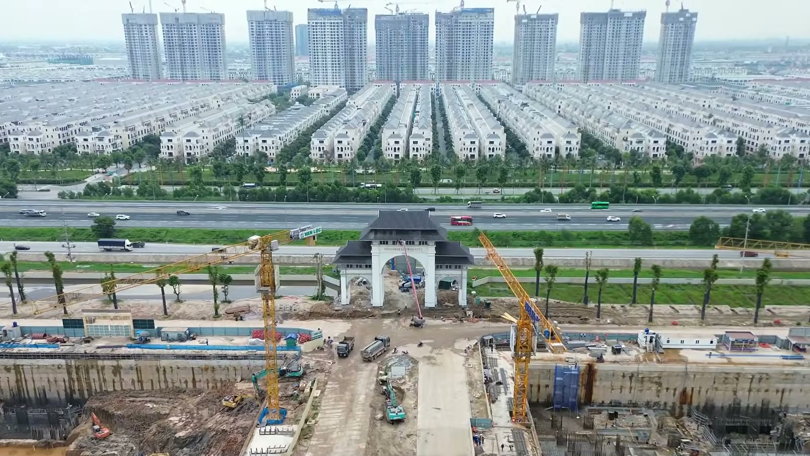 Cổng vào Sunshine Legend City đang hoàn thiện bên đường cao tốc Hà Nội – Hải Phòng, phía sau cao tốc là dãy nhà thấp tầng của Vinhomes Ocean Park 2