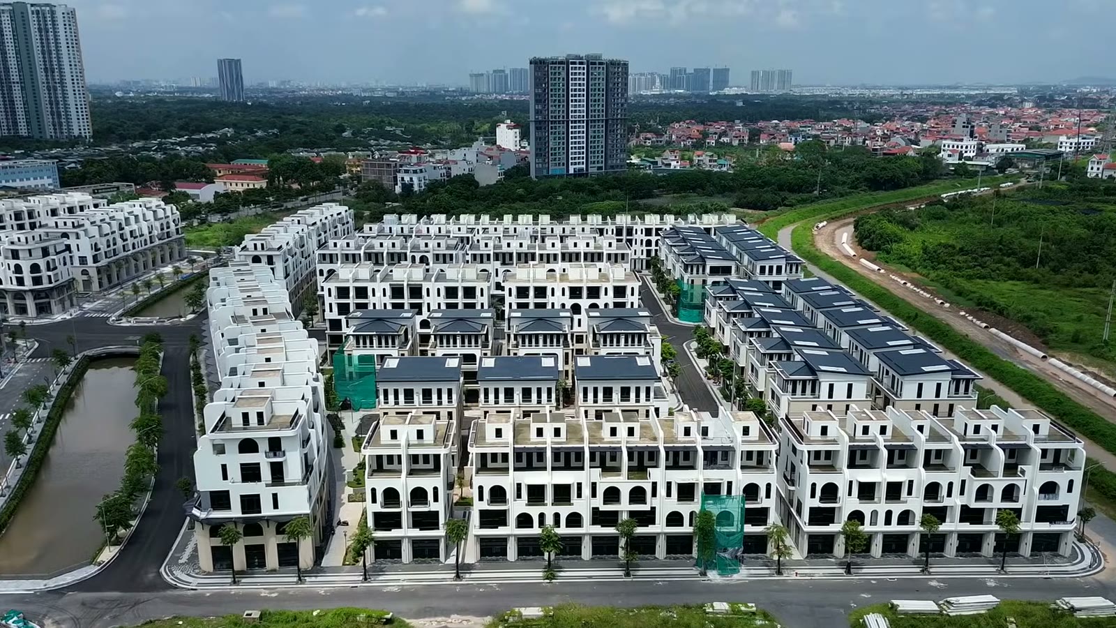 Các dãy nhà thấp tầng màu trắng của Vaquarius Văn Giang nhìn từ trên cao, một nhánh nước chạy giữa hai dãy và tòa cao tầng đang xây phía bên trái